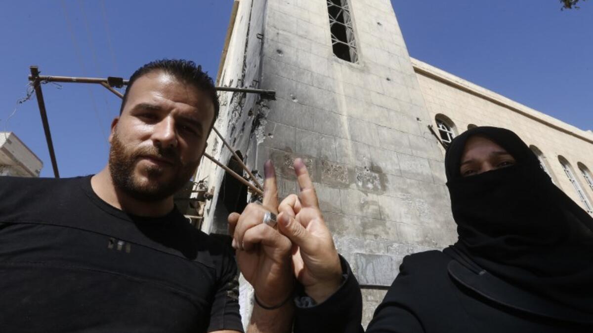 A man and a woman show their ink-stained index fingers after voting for Syria's first local elections since 2011. (LOUAI BESHARA / AFP)