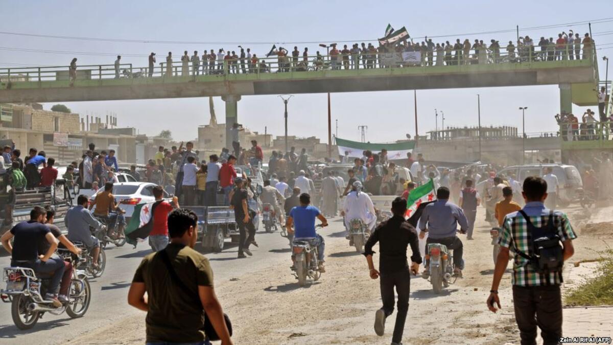 Syrians chant slogans and wave flags of the opposition as they protest against a promised government assault on Idlib province. (Zein Al RIFAI / AFP)