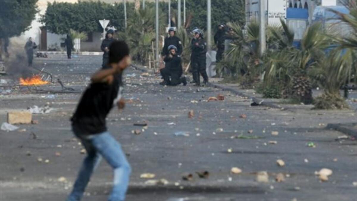 A member of the Tunisian security forces takes aim towards a Tunisian demonstrator who prepares to throw a rock towards them during clashes between demonstrators and security forces in Regueb, near Sidi Bouzid.