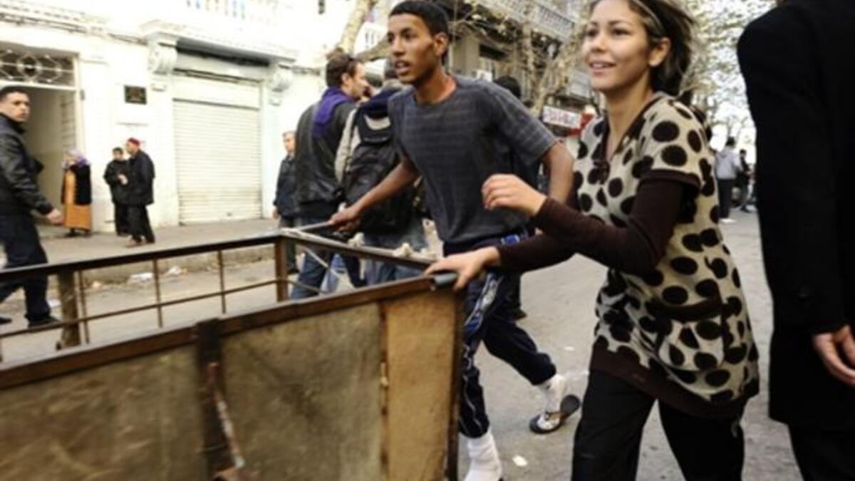 Residents run to take goods from a destroyed store. There were scenes of looting overnight in the suburbs of Tunis.