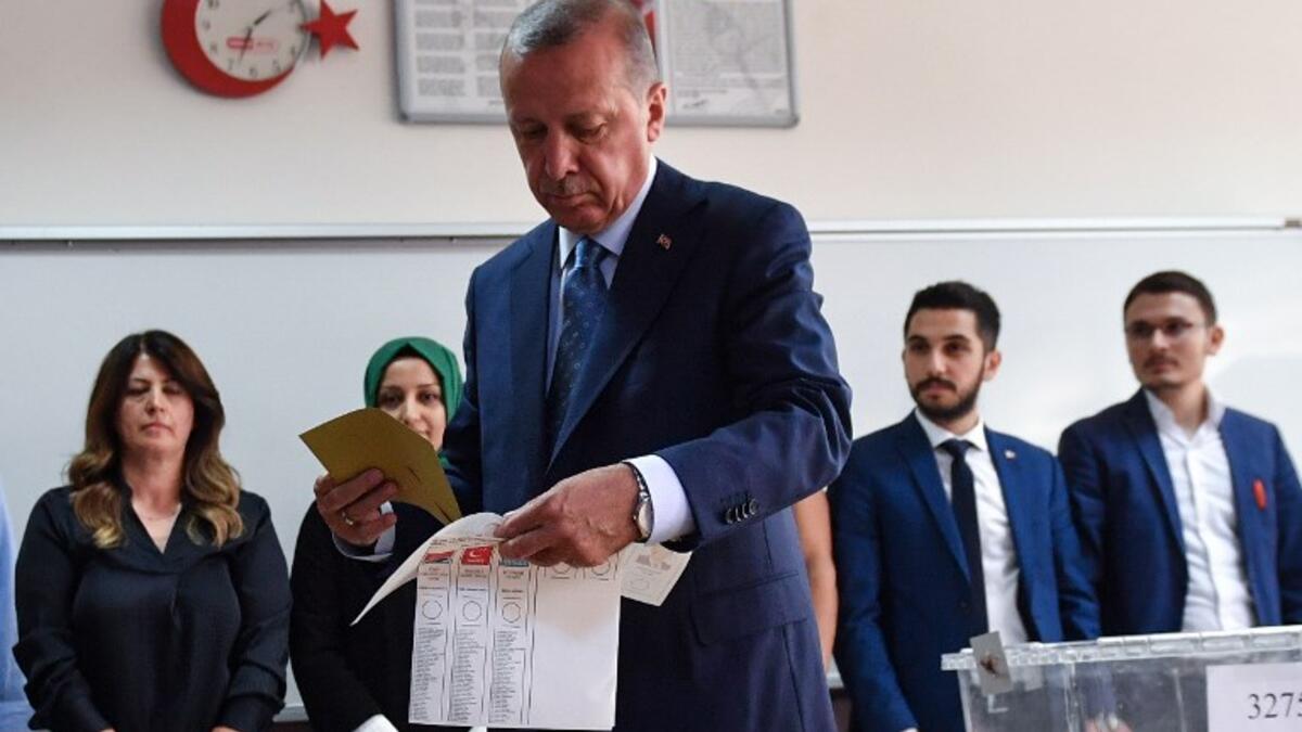 Turkey's President and leader of the Justice and Development Party (AKP) Recep Tayyip Erdogan looks at his ballot before casting his vote at a polling station during snap twin Turkish presidential and parliamentary elections in Istanbul on June 24, 2018.(Bulent Kilic/ AFP)
