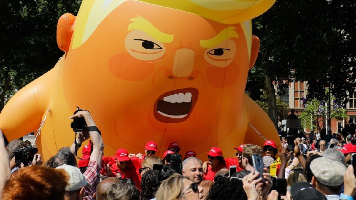 Activists inflate a giant balloon depicting US President Donald Trump as an orange baby during a demonstration against Trump's visit to the UK in Parliament Square in London on July 13, 2018.  (Tolga AKMEN / AFP)