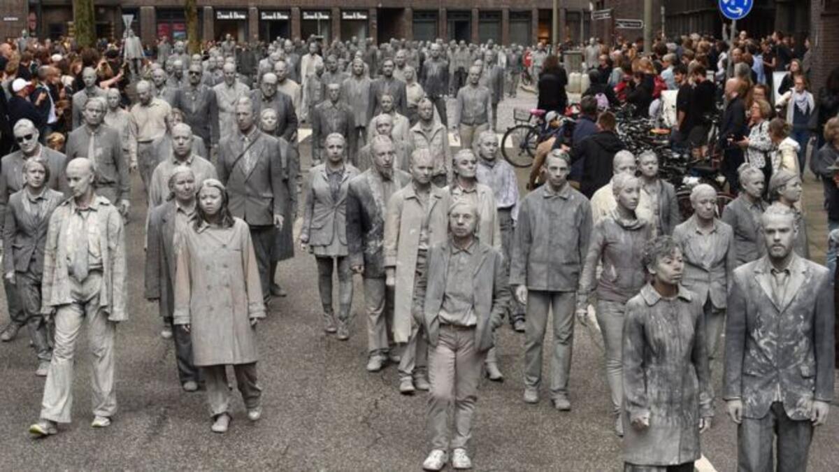 أشخاص ملطخون بالطين يشاركون في عمل فني بعنوان "ألف شخصية" في الخامس من يوليو/تموز 2017 في شوارع هامبورغ، احتجاجا على قمة مجموعة العشرين.