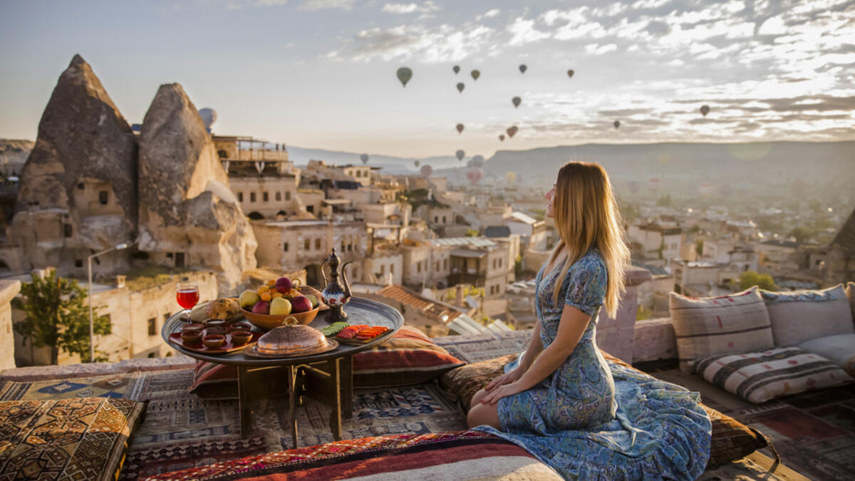 A woman sits on one of the Cappadocia roof in early morning sunrise, when balloons fly (Shutterstock/File Photo)