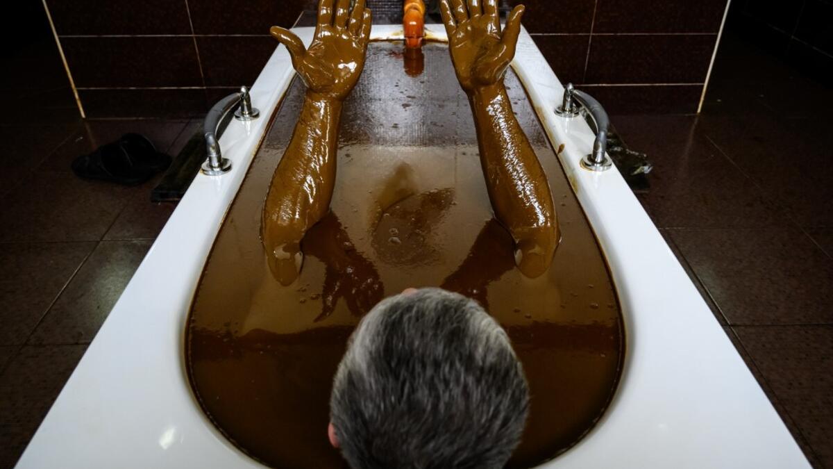 A man bathes in a tub filled with Naftalan crude oil during a treatment session at Sehirli Naftalan Health Center, some 300 kilometres (186 miles) from capital Baku, on March 21, 2019. Immersed up to her neck in crude oil, a Russian woman suffering from joint disease smiles in delight, confident that the treatment at a spa in northwestern Azerbaijan will cure her painful condition.  Mladen ANTONOV / AFP