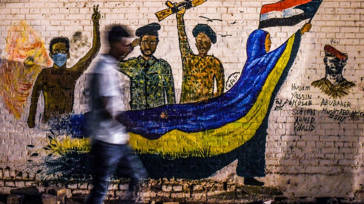 A Sudanese protester walks past a recently painted mural during a demonstration near the army headquarters in the capital Khartoum (AFP)