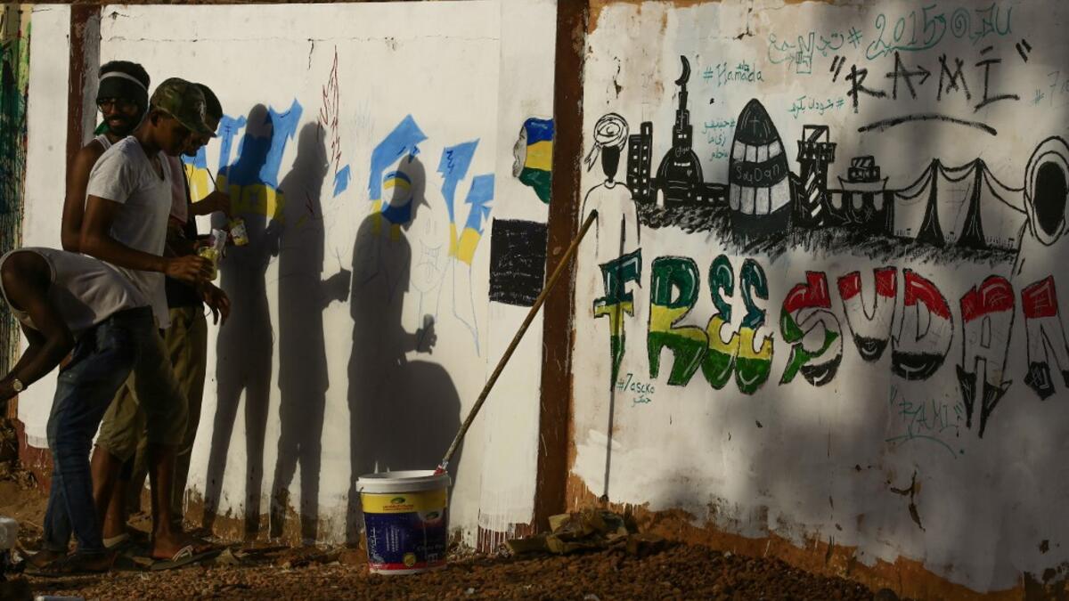 Sudanese protesters paint a graffiti during a "million-strong" march outside the army headquarters in the capital Khartoum. ASHRAF SHAZLY / AFP