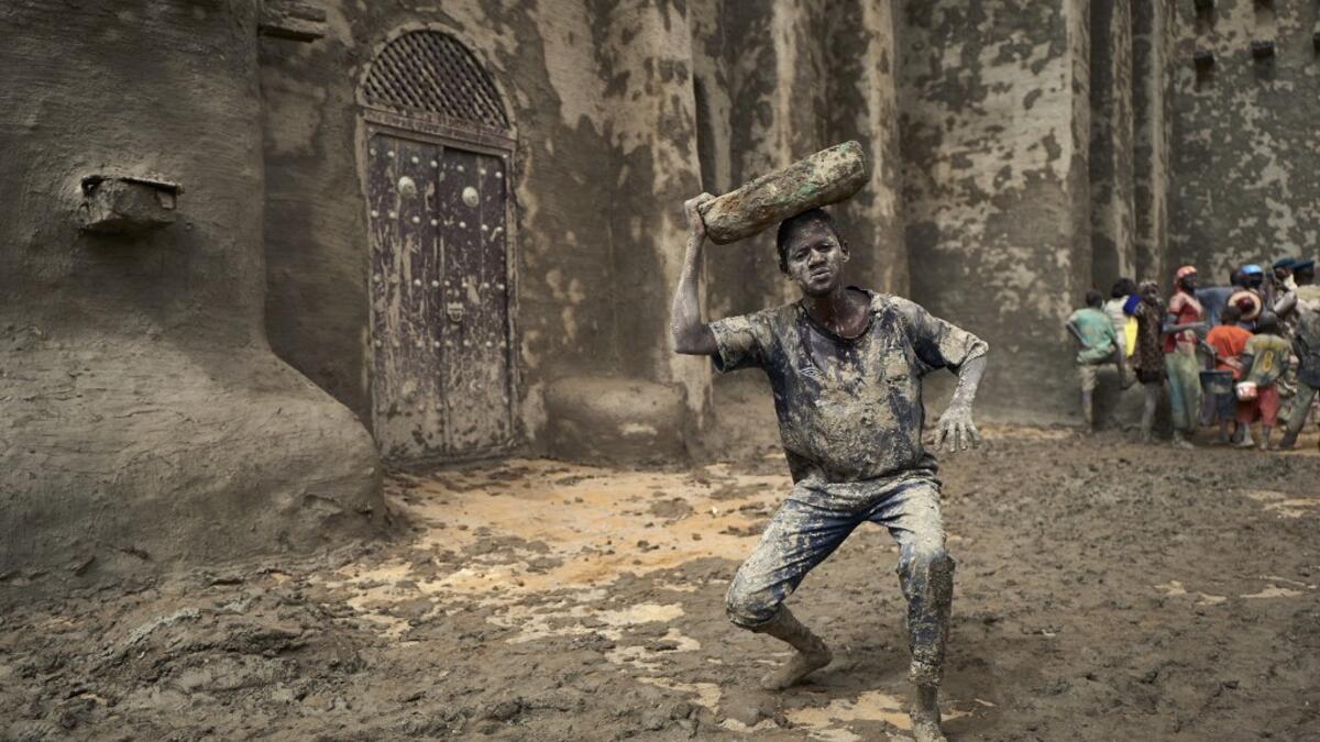 A man takes part in the annual rendering of the Great Mosque of Djenne in central Mali  MICHELE CATTANI / AFP