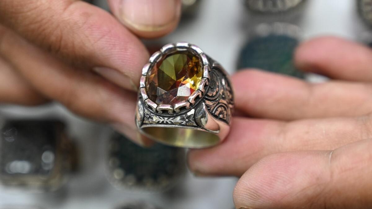 Hadi Ekhlas, engraver, holds one of his work on his hand at his workshop at the Grand Bazaar in Istanbul.  OZAN KOSE / AFP