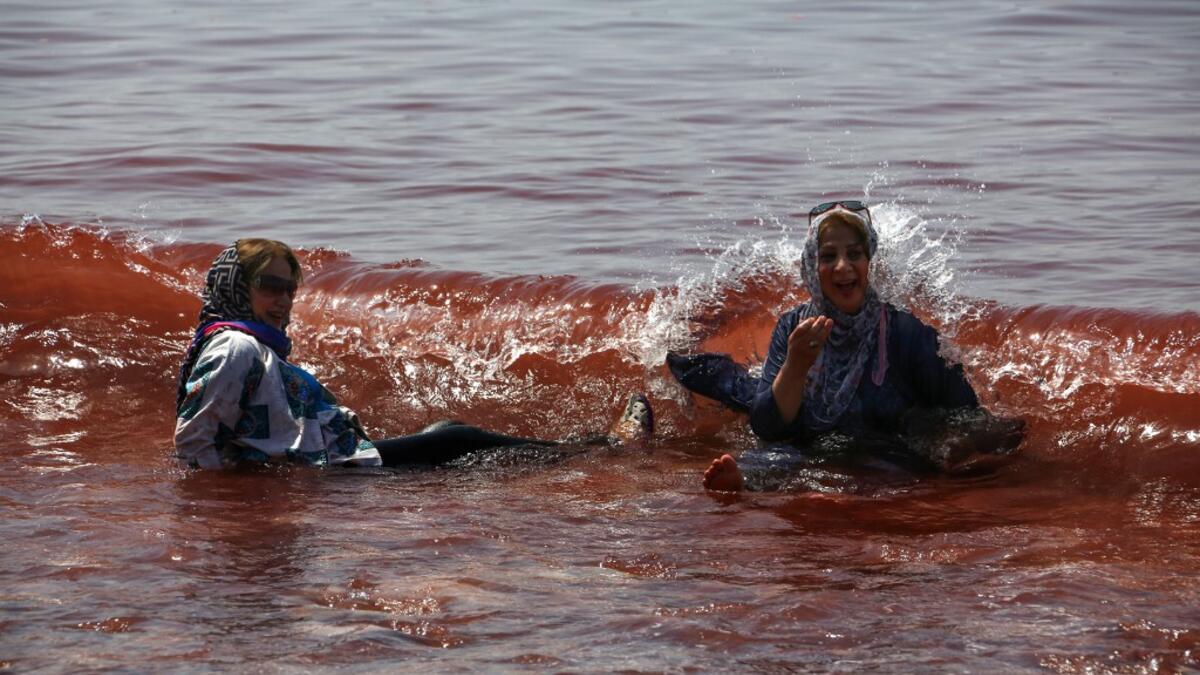Visitors paddle in the water on the Hormuz Island in the Gulf Strait of Hormuz, off the Iranian port city of Bandar Abbas, on April 29, 2019.  ATTA KENARE / AFP