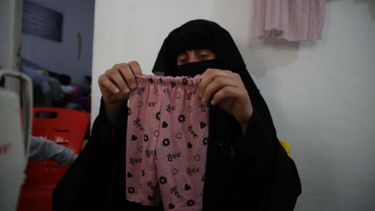 Hasna Dbeis, a 30-year-old former detainee in a Syrian-regime jail, shows baby trousers that she has sewn at a workshop employing former female detainees, in the town of Maarat Nasrin, in the rebel-held part of the Syrian Idlib province  Aaref WATAD / AFP
