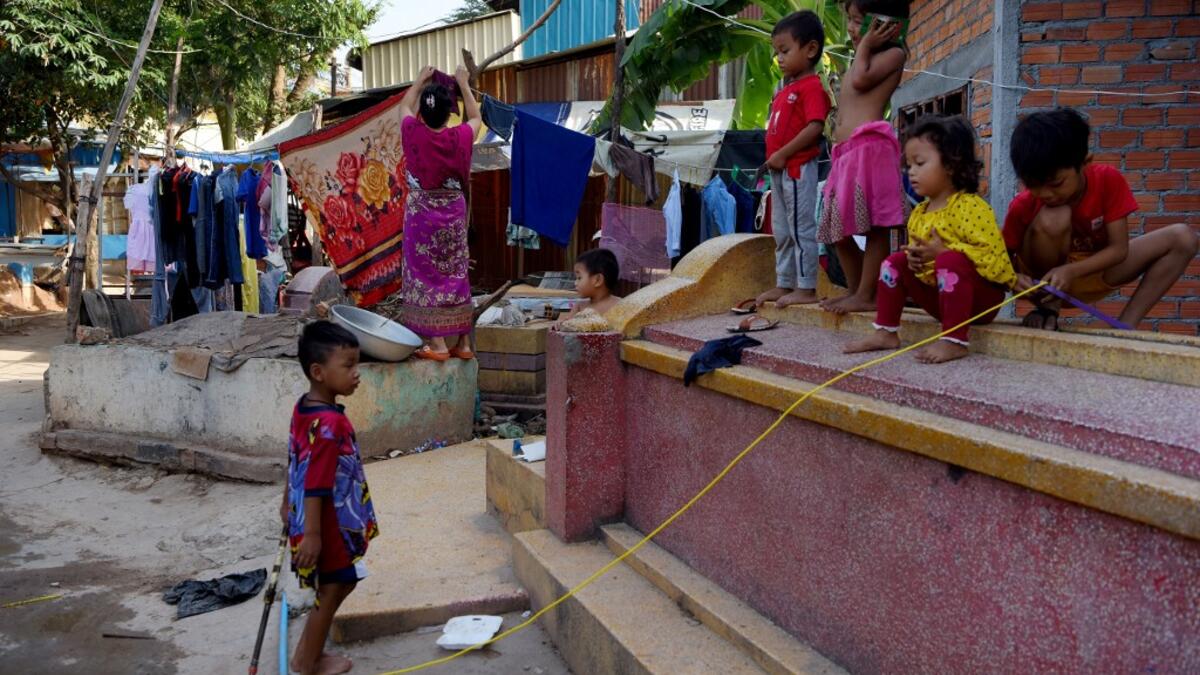 This picture shows children playing on a grave as a woman dries her clothes on another grave in Phnom Penh.  TANG CHHIN Sothy / AFP