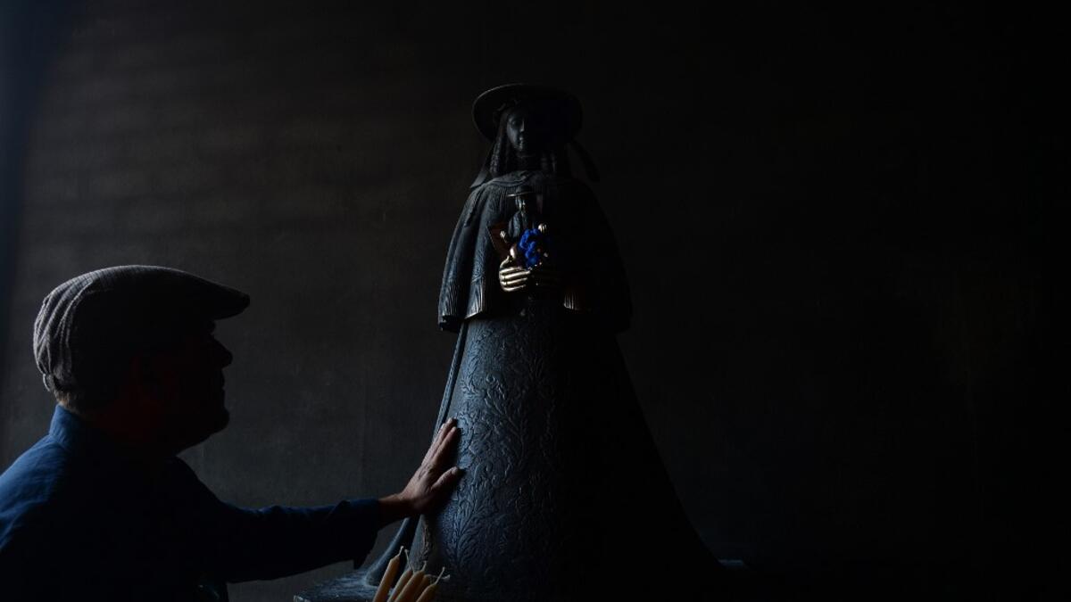 A pilgrim touches the effigy of the Rocio Virgin at the church of the village of El Rocio on June 10, 2019. CRISTINA QUICLER / AFP