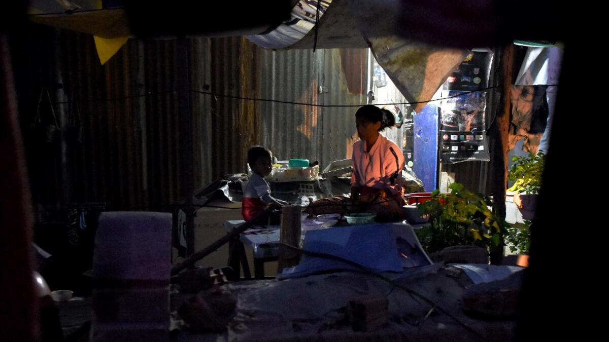 This picture  shows a woman and her child preparing dinner next to graves outside their home in Phnom Penh.  TANG CHHIN Sothy / AFP