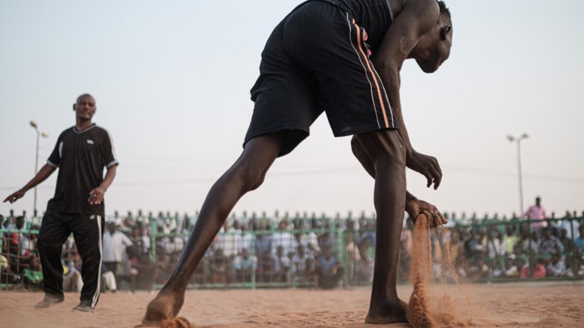 A Sudanese wrestler scoops sand during a traditional Nuba wrestling match at the Haj Youssef stadium in the district of Khartoum.  Yasuyoshi CHIBA / AFP