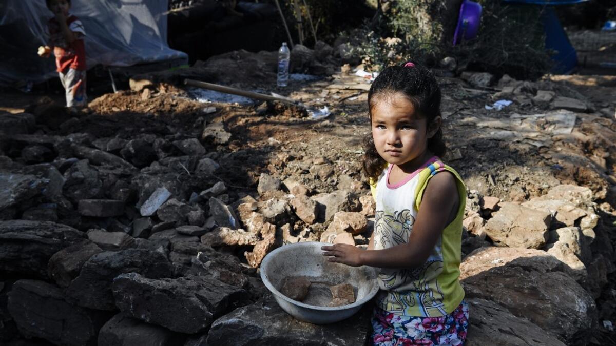 A girl gazes at the makeshift part of the Samos refugee camp, just above the island's capital city of Vathy.  LOUISA GOULIAMAKI / AFP