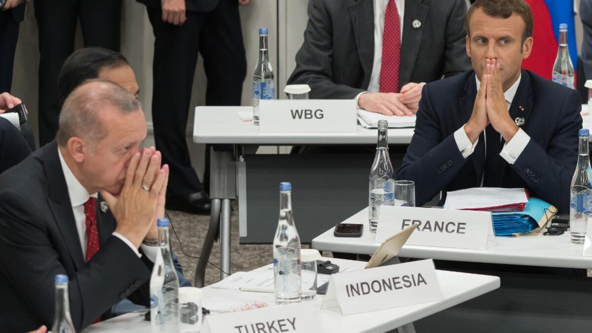 Turkey's President Recep Tayyip Erdogan (L) and France's President Emmanuel Macron gesture as they attend a meeting on the digital economy at the G20 Summit in Osaka on June 28, 2019.  Jacques Witt / POOL / AFP