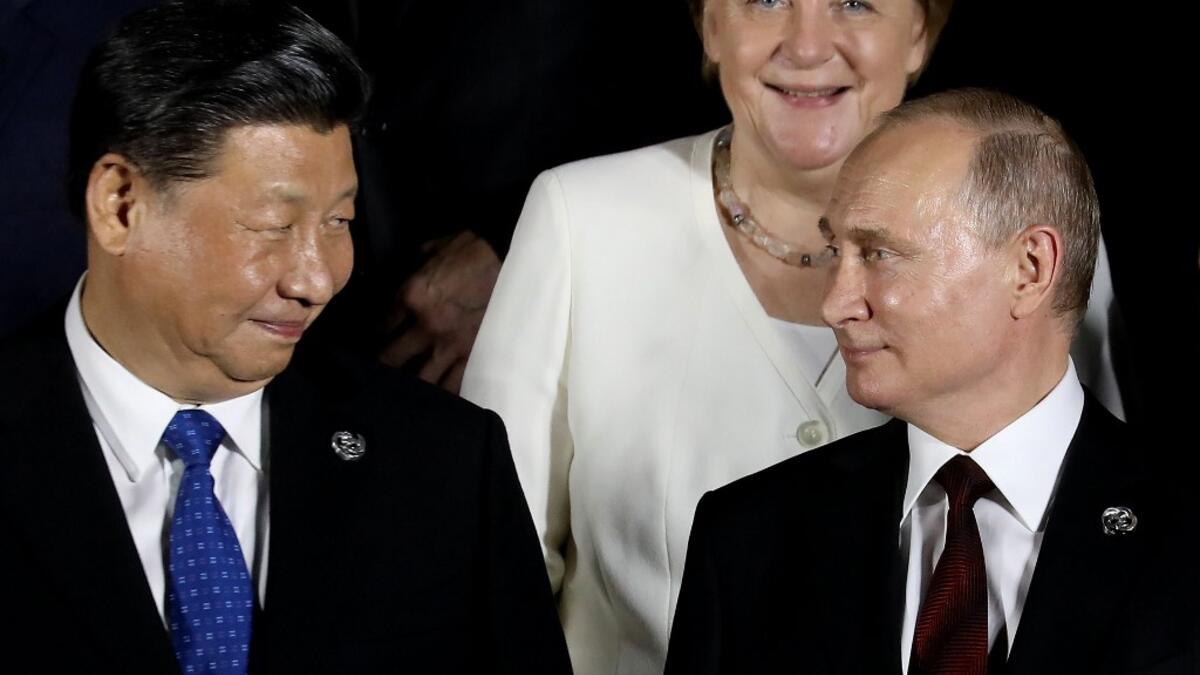 German Chancellor Angela Merkel stands behind Russian President Vladimir Putin (front R) and Chinese President Xi Jinping as they arrive to pose for a group photo before a cultural event at the Osaka Geihinkan in Osaka Castle Park during the G20 Summit in Osaka on June 28, 2019.  Dominique JACOVIDES / POOL / AFP