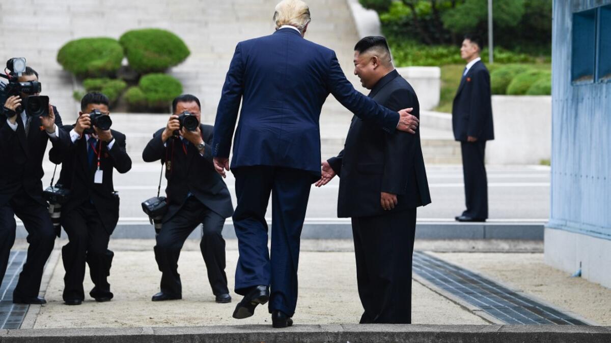 US President Donald Trump steps into the northern side of the Military Demarcation Line that divides North and South Korea, as North Korea's leader Kim Jong Un looks on, in the Joint Security Area (JSA) of Panmunjom in the Demilitarized zone (DMZ) on June 30, 2019.  Brendan Smialowski / AFP