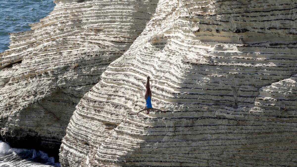 A cliff diver jumps from a platform on the landmark Raouche sea rock off the coast of the Lebanese capital Beirut on July 14, 2019, during the women's 2019 Red Bull Cliff Diving World Series.  ANWAR AMRO / AA / AFP