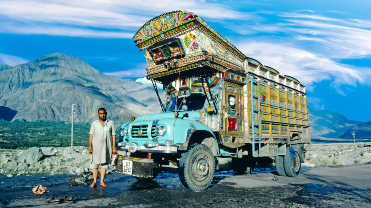 Proud truck driver presents his painted truck at the karacorum highway in Pakistan. The Karakoram highway connects Pakistan with China (Shutterstock)