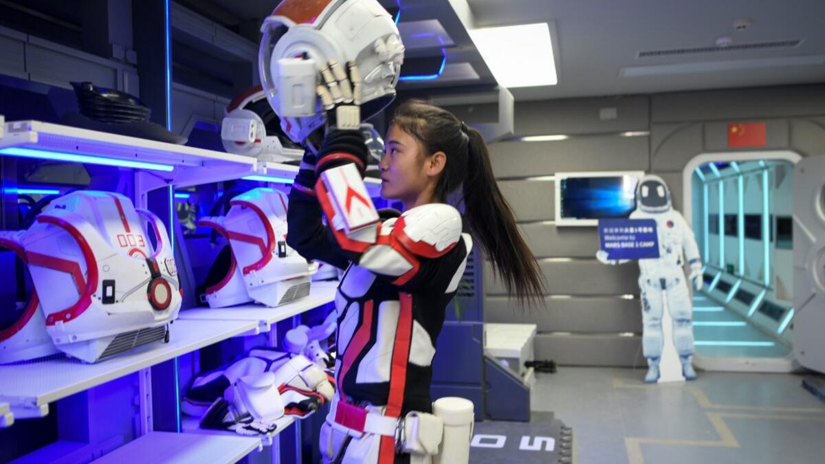 A guide wearing a spacesuit puts on a helmet at "Mars Base 1", a C-Space Project, in the Gobi desert, some 40 kilometres from Jinchang in China's northwest Gansu province on April 17, 2019. WANG ZHAO / AFP