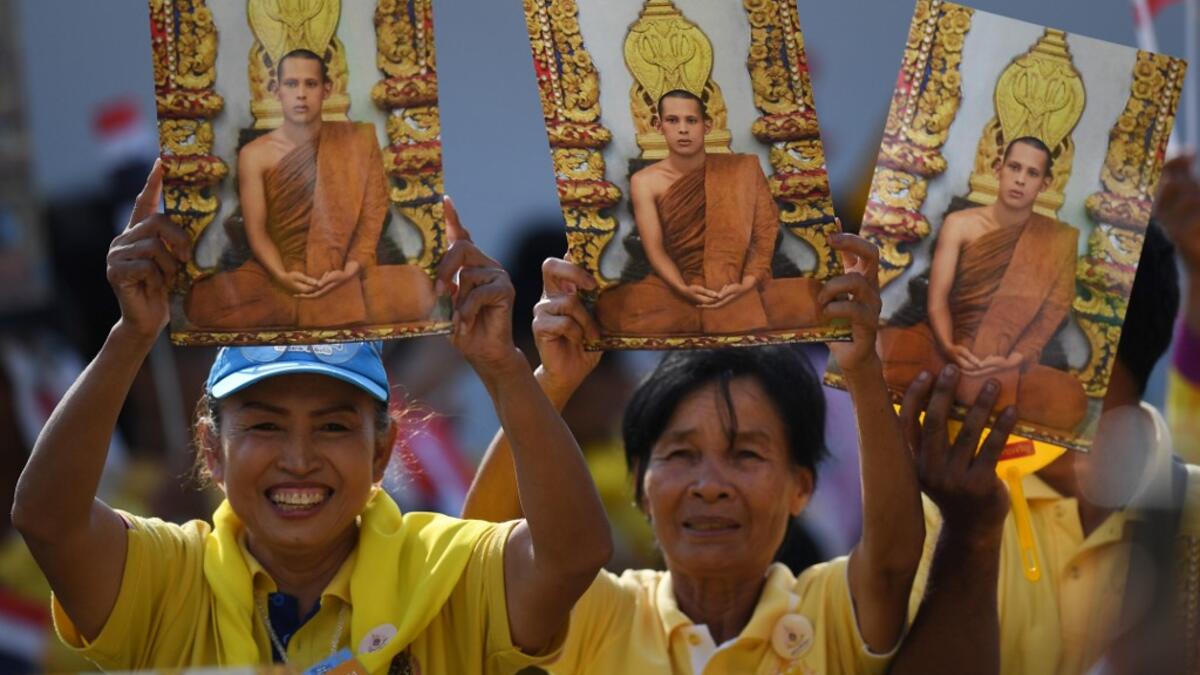 People hold portraits of Thailand's King Maha Vajiralongkorn as they wait for him and Queen Suthida to appear on the balcony of Suddhaisavarya Prasad Hall of the Grand Palace to grant a public audience on the final day of his royal coronation in Bangkok on May 6, 2019.  Lillian SUWANRUMPHA / AFP
