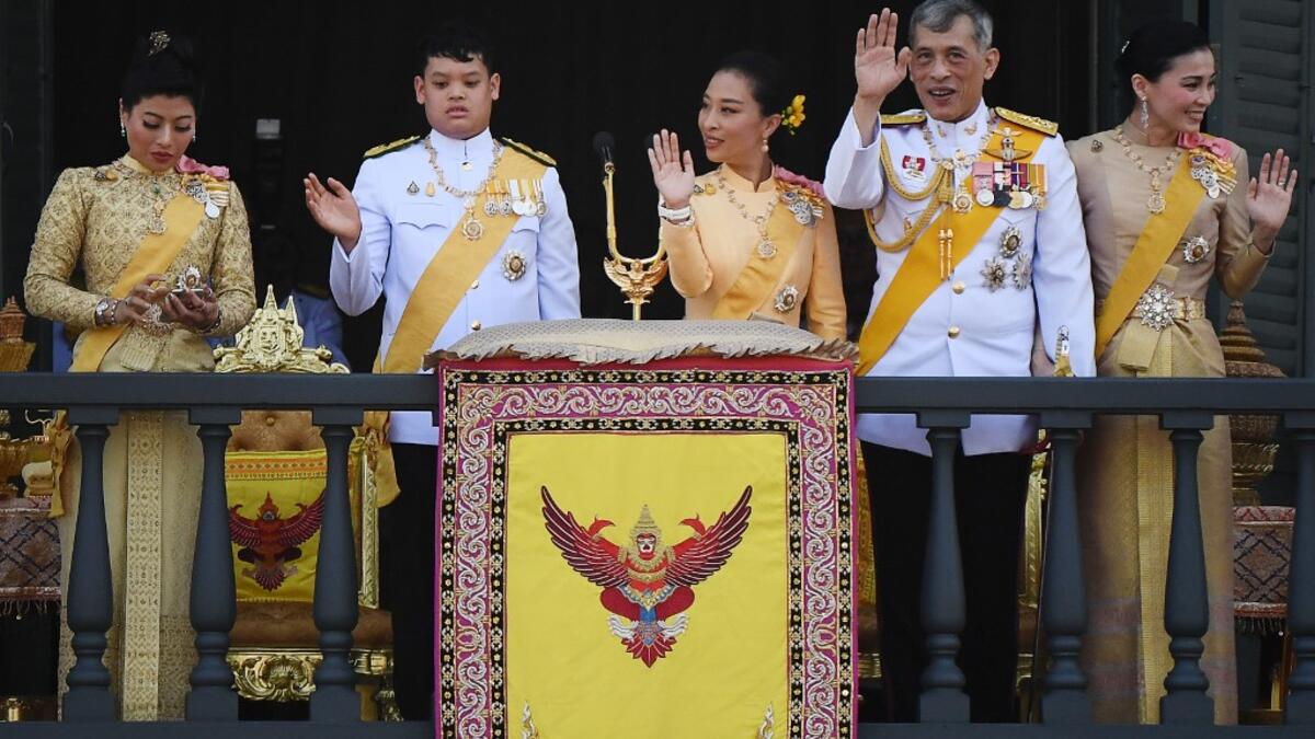 (From L to R) Thailand's Princess Sirivannavari Nariratana uses her mobile phone as her brother Prince Dipangkorn Rasmijoti, sister Princess Bajrakitiyabha Mahidol, father King Maha Vajiralongkorn and Queen Suthidawave to well-wishers from the balcony of Suddhaisavarya Prasad Hall. Jewel SAMAD / AFP