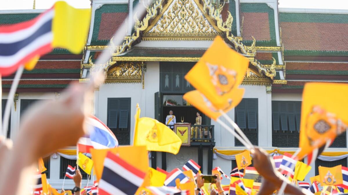 Thailand's King Maha Vajiralongkorn and Queen Suthida appear on the balcony of Suddhaisavarya Prasad Hall of the Grand Palace while people wave Thailand national flag and royal flag as they grant a public audience on the final day of his royal coronation in Bangkok on May 6, 2019.  Manan VATSYAYANA / AFP