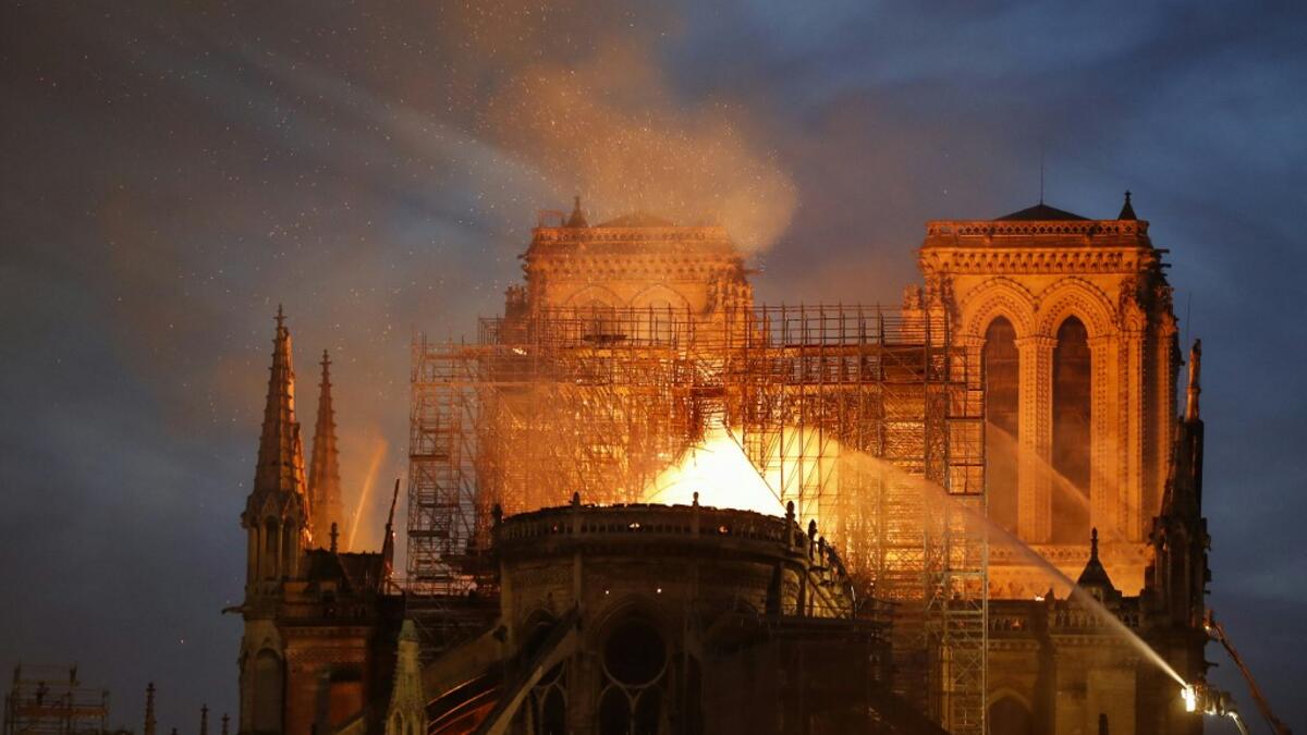 A Firefighter douse flames billowing from the roof at Notre-Dame Cathedral in Paris on April 15, 2019. A major fire broke out at the landmark Notre-Dame Cathedral in central Paris sending flames and huge clouds of grey smoke billowing into the sky. FRANCOIS GUILLOT / AFP