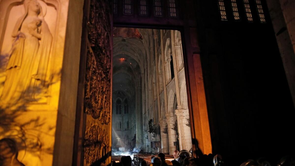 This general view from the entrance shows smoke rising in front of the altar cross at Notre-Dame Cathedral in Paris on April 15, 2019, after a fire engulfed the building. PHILIPPE WOJAZER / POOL / AFP