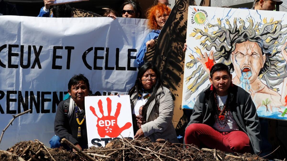 Members of indigenous tribes from the Amazon demonstrate alongside activists of 'Extinction Rebellion' (XR) against large hydroelectric dams in front of the Grande Arche de La Defense in Puteaux, northwest of Paris, on May 14, 2019. FRANCOIS GUILLOT / AFP