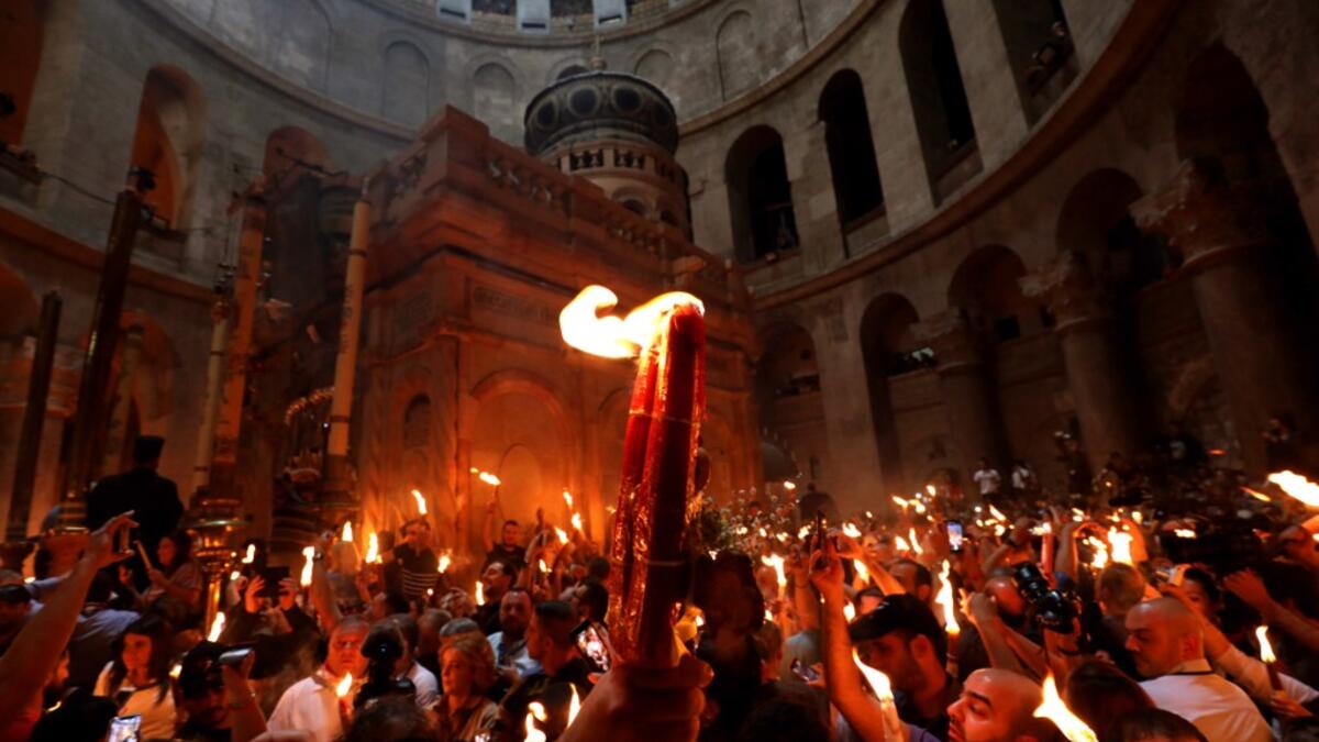 Christian Orthodox worshippers hold up candles lit from the ‘Holy Fire’ as they gather in the Church of the Holy Sepulchre in Jerusalem’s Old City on April 27, 2019. GALI TIBBON / AFP