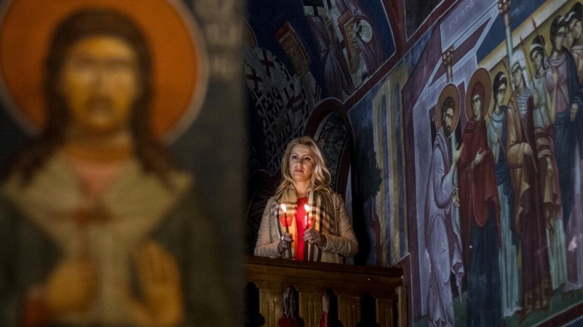 A North Macedonian Orthodox Christian woman holds candles as she takes part in midnight Easter services at the Kalishta Monastery, in the village of Kalishta near Struga, on April 27, 2019.  Robert ATANASOVSKI / AFP