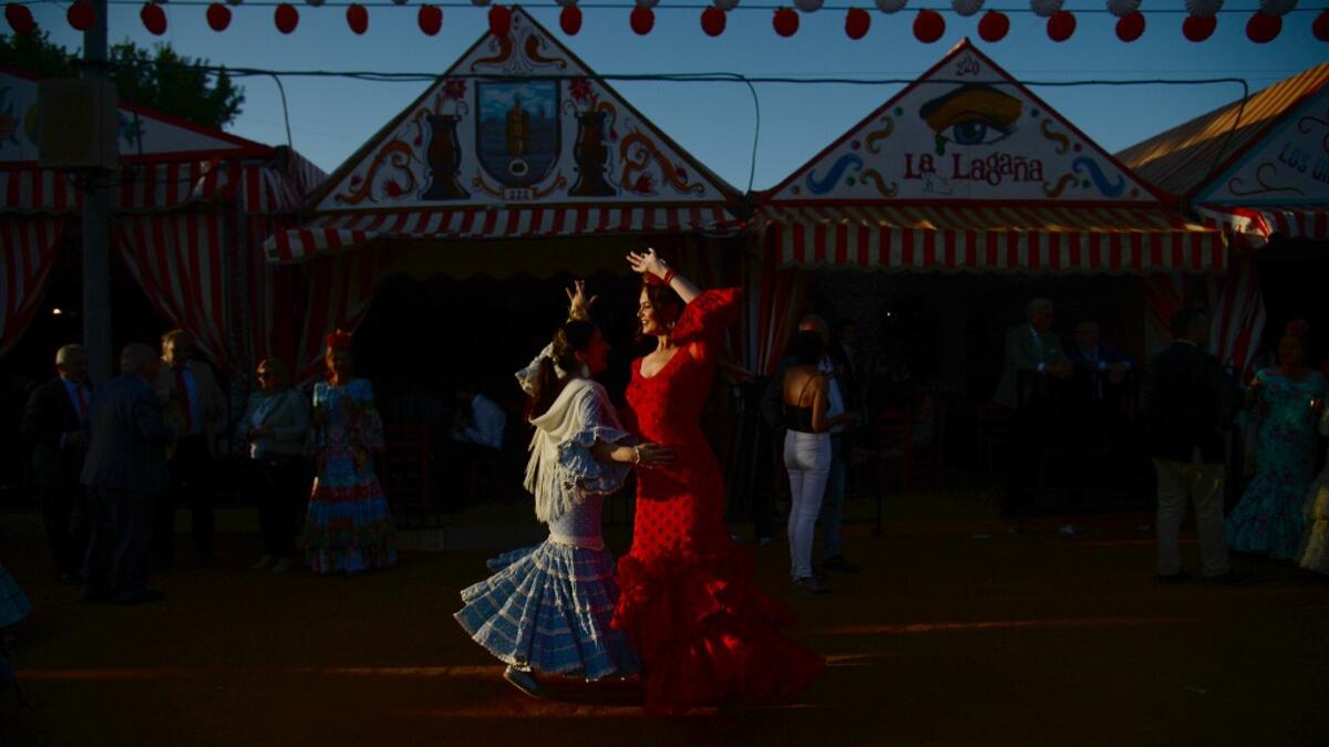 Women in traditional Sevillian dresses dance during the "Feria de Abril" (April Fair) festival in Seville on May 6, 2019. The fair dates back to 1847 when it was originally organized as a livestock fair but has turned into a week of flamenco dancing, music and bullfighting.  CRISTINA QUICLER / AFP