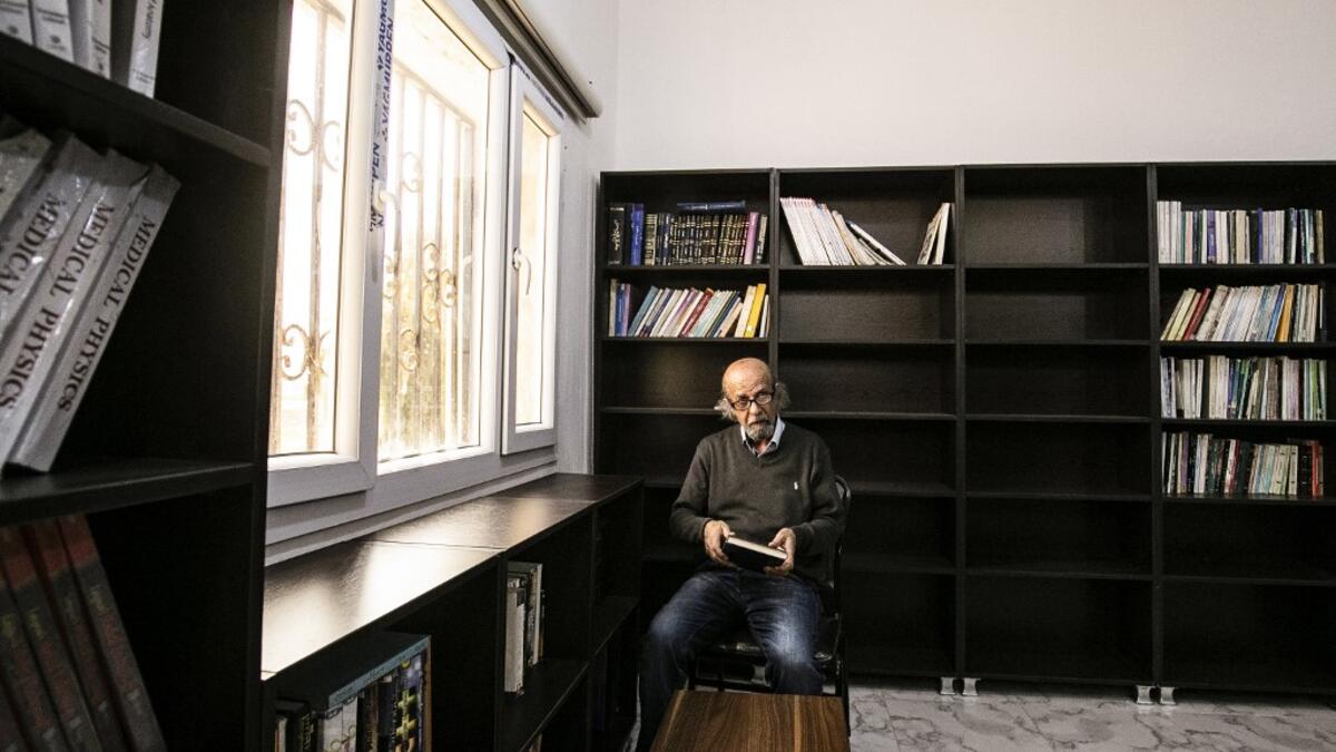 Ziad al-Hamad, director of the first cultural centre to open since ISIS rule ended in the eastern Syrian city of Raqa. He holds a book as he sits in its library on May 1, 2019. Delil souleiman / AFP