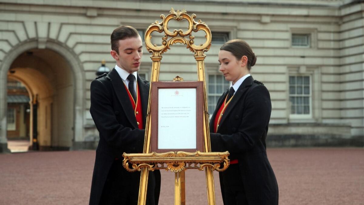 Footmen Stephen Kelly and Sarah Thompson set up an official notice on an easel at the gates of Buckingham Palace in London on May 6, 2019, announcing the birth of a son to Britain's Prince Harry, Duke of Sussex and Meghan, Duchess of Sussex. Yui Mok / POOL / AFP